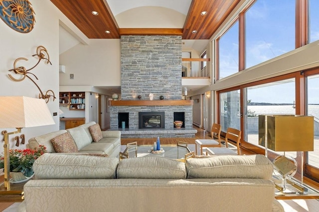 living area featuring high vaulted ceiling, recessed lighting, a stone fireplace, and wood finished floors