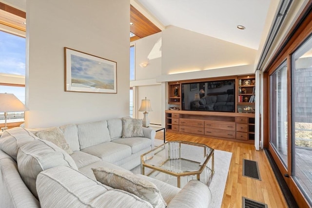 living area featuring light wood-style floors, visible vents, and high vaulted ceiling