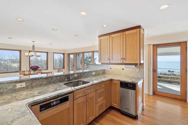 kitchen featuring a peninsula, a water view, a sink, dishwasher, and decorative light fixtures