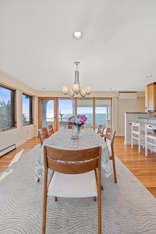 dining area featuring a water view, light wood-type flooring, a chandelier, and a wealth of natural light