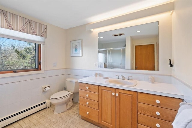 bathroom featuring tile walls, a baseboard heating unit, a stall shower, wainscoting, and vanity