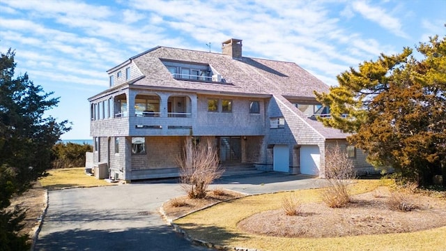 view of front facade with driveway, a garage, and a chimney