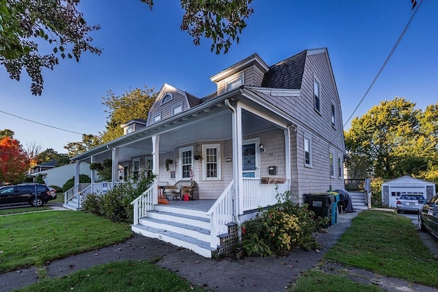 view of front of property with a front yard, a porch, and an outdoor structure