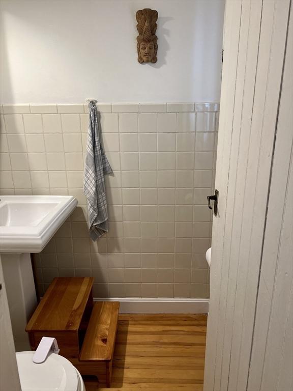 20 Rushmore St Unit 20, Boston, MA 02135 - half bathroom with wood finished floors, a wainscoted wall, tile walls, and toilet