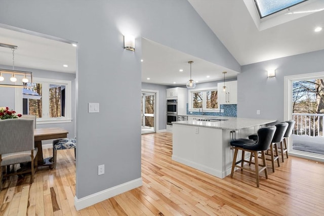 kitchen with tasteful backsplash, stainless steel double oven, a healthy amount of sunlight, and white cabinetry