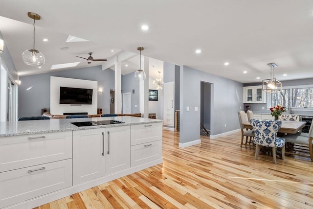 kitchen with open floor plan, white cabinets, light wood-style flooring, and black electric stovetop