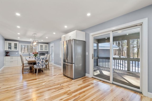 kitchen featuring light wood-type flooring, a center island, white cabinets, and freestanding refrigerator