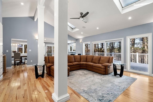 living area with a skylight, recessed lighting, a ceiling fan, high vaulted ceiling, and light wood-type flooring