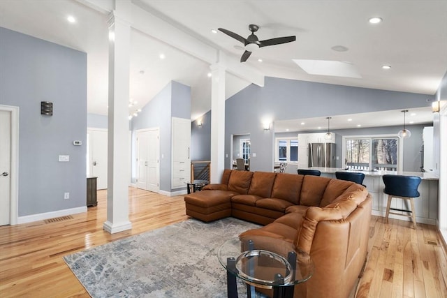 living area with light wood finished floors, a ceiling fan, high vaulted ceiling, beamed ceiling, and baseboards