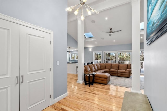 living area featuring a skylight, light wood-style flooring, high vaulted ceiling, and a wealth of natural light