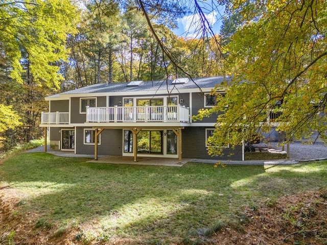 back of property with a deck, a lawn, and a patio