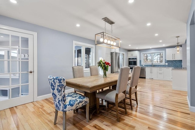 dining space featuring baseboards, light wood finished floors, and recessed lighting