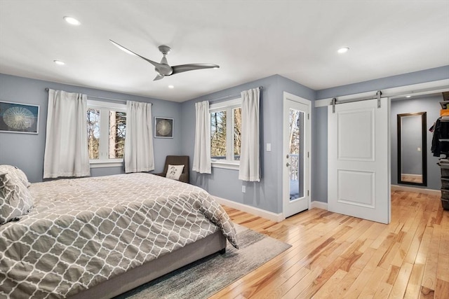 bedroom featuring recessed lighting, wood-type flooring, a barn door, ceiling fan, and baseboards