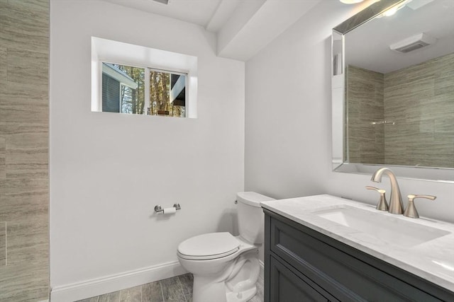 full bath with toilet, wood finished floors, vanity, baseboards, and a tile shower