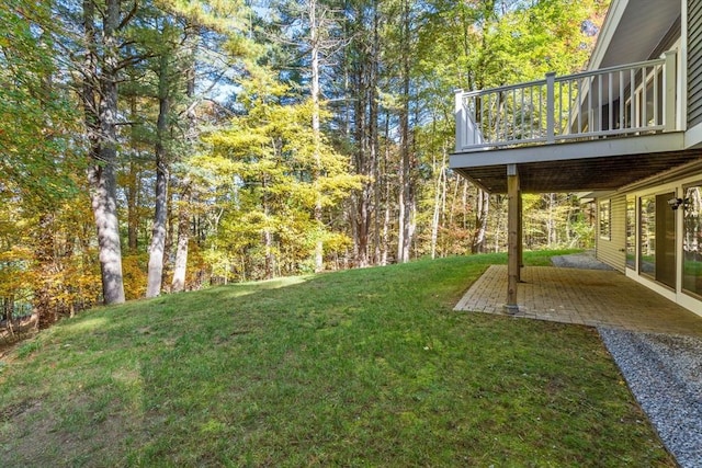 view of yard featuring a forest view, a patio area, and a wooden deck