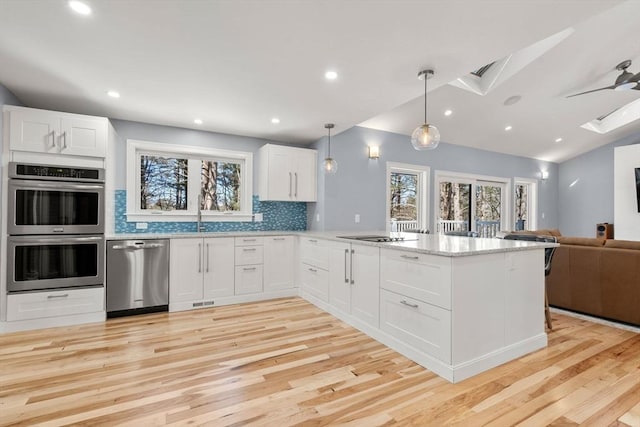 kitchen featuring stainless steel appliances, open floor plan, plenty of natural light, and a peninsula