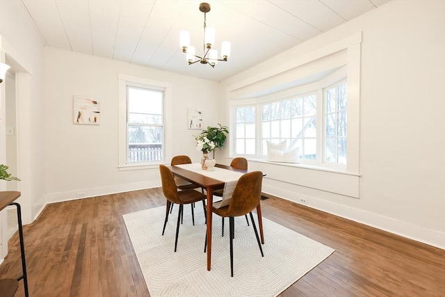 dining area with a healthy amount of sunlight, dark wood-type flooring, and a chandelier