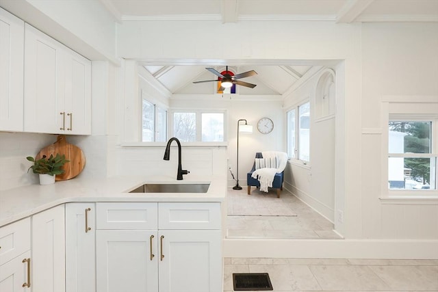 kitchen featuring sink, decorative backsplash, lofted ceiling with beams, and white cabinets