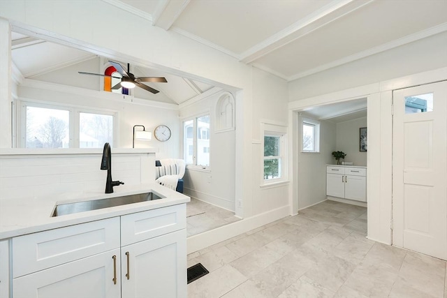 kitchen with white cabinetry, sink, vaulted ceiling with beams, and ceiling fan