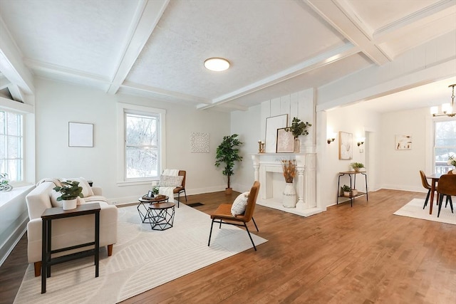 sitting room with a notable chandelier, beam ceiling, wood-type flooring, and plenty of natural light