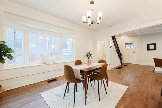 dining room with hardwood / wood-style flooring, a chandelier, and beam ceiling