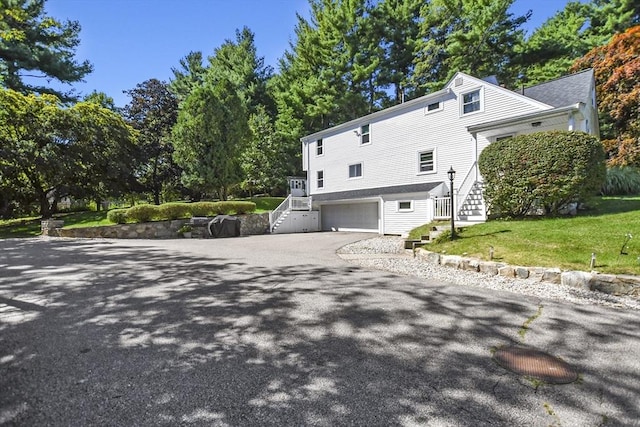 view of property exterior with a yard, driveway, stairs, and a garage