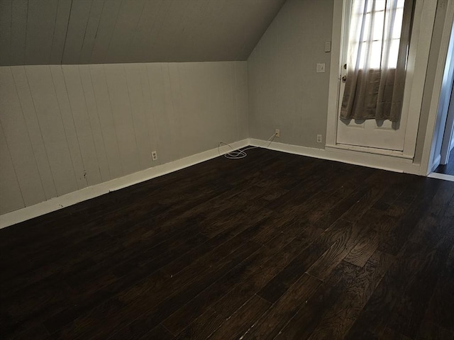 additional living space featuring baseboards, dark wood finished floors, and vaulted ceiling