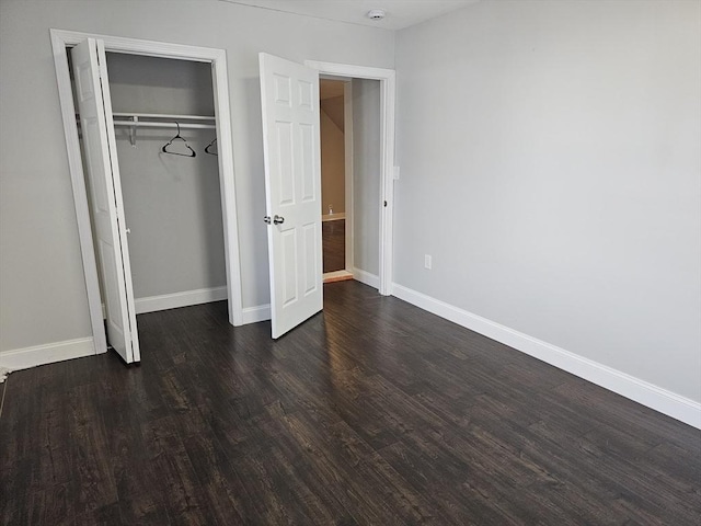 unfurnished bedroom with dark wood-style floors, a closet, and baseboards