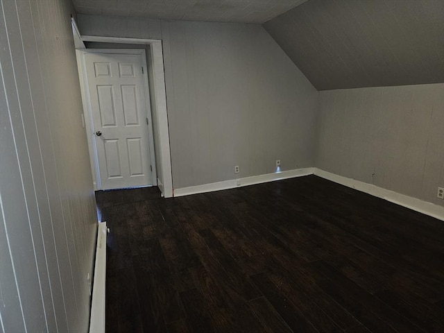 bonus room featuring wooden walls, baseboards, a baseboard radiator, dark wood finished floors, and lofted ceiling