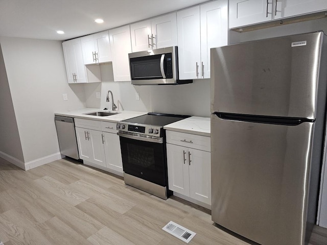 kitchen featuring light wood finished floors, visible vents, appliances with stainless steel finishes, white cabinetry, and a sink