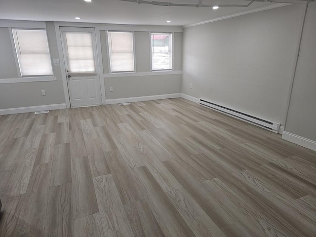 unfurnished room with baseboard heating, light wood-type flooring, and baseboards