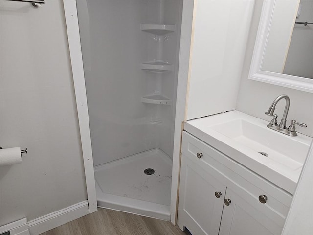 bathroom with vanity, wood finished floors, a stall shower, and baseboards