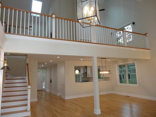 interior space with an inviting chandelier, a towering ceiling, and light wood-type flooring