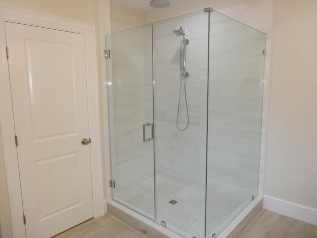 bathroom featuring wood-type flooring and a shower with shower door