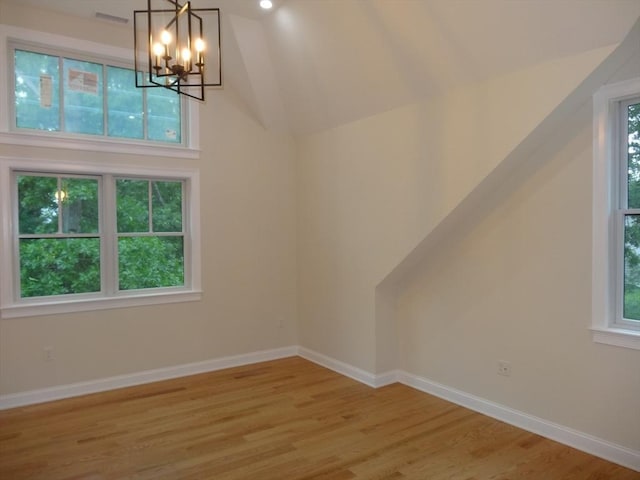 bonus room with lofted ceiling, a notable chandelier, and light wood-type flooring