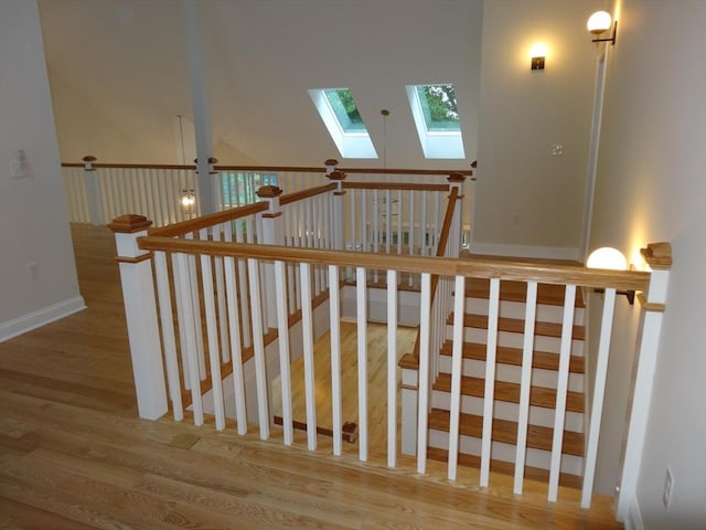 stairway with hardwood / wood-style flooring and vaulted ceiling with skylight