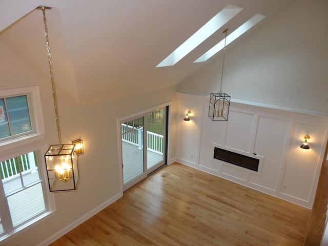 unfurnished living room featuring high vaulted ceiling and light hardwood / wood-style floors