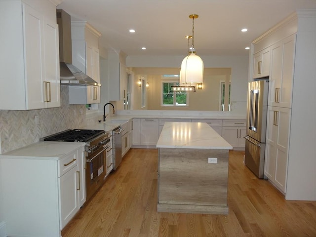 kitchen with white cabinetry, light stone counters, a center island, premium appliances, and wall chimney range hood