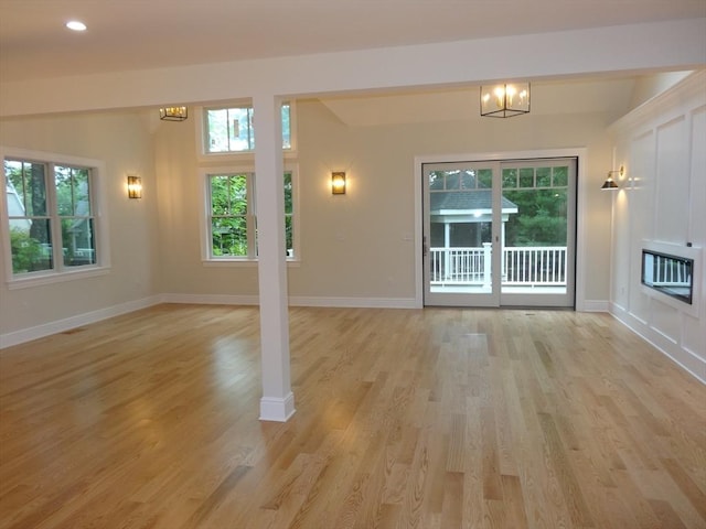 unfurnished living room featuring a notable chandelier, heating unit, and light hardwood / wood-style flooring