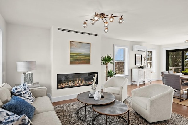 living room featuring hardwood / wood-style flooring, an AC wall unit, and a chandelier