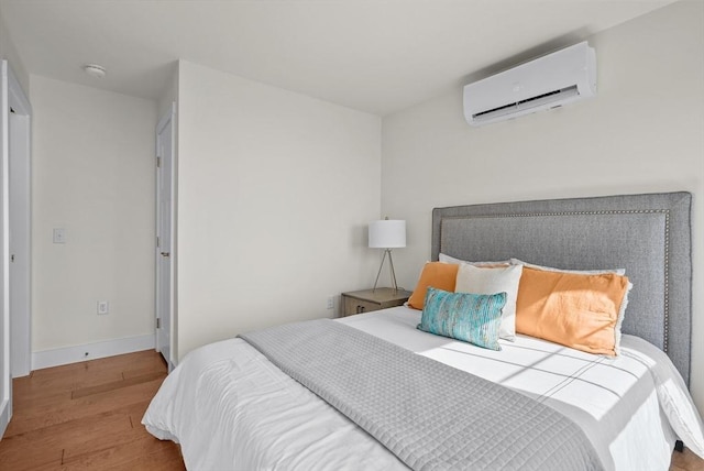 bedroom with light hardwood / wood-style floors and a wall mounted air conditioner