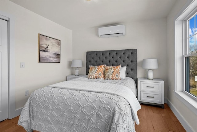 bedroom with a wall mounted air conditioner and light hardwood / wood-style flooring