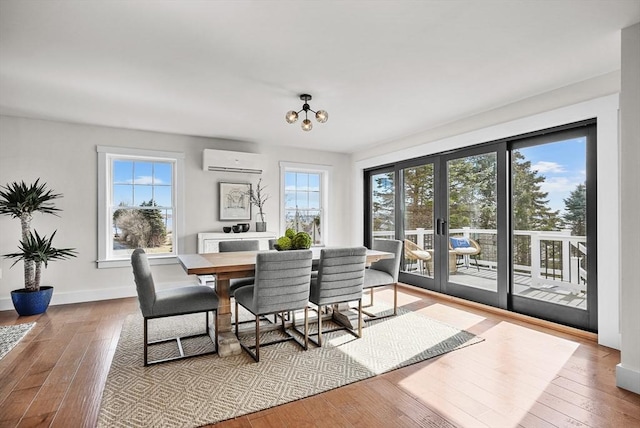 dining area with a wall mounted air conditioner, a notable chandelier, and light hardwood / wood-style flooring