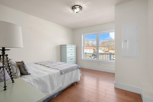 bedroom with electric panel and light wood-type flooring