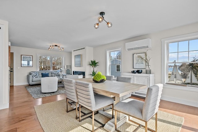 dining room featuring light hardwood / wood-style flooring, a wall mounted AC, and a notable chandelier