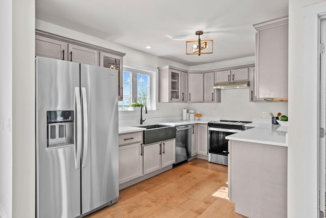 kitchen with gray cabinetry, sink, stainless steel appliances, and light wood-type flooring