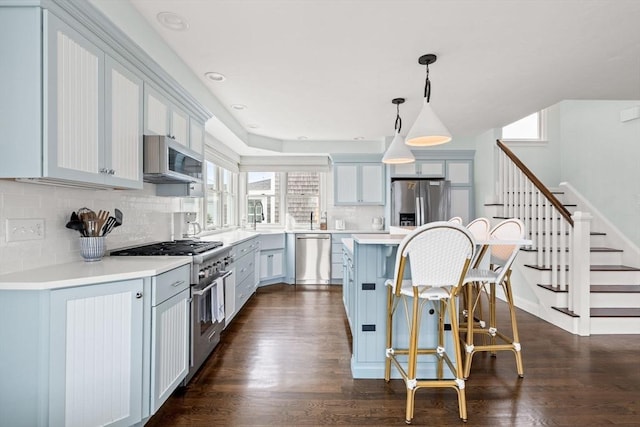 77 Lighthouse Rd, Scituate, MA 02066 - kitchen featuring appliances with stainless steel finishes, a breakfast bar, backsplash, dark wood-style floors, and a kitchen island