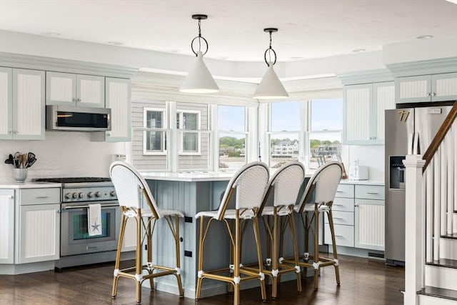 77 Lighthouse Rd, Scituate, MA 02066 - kitchen with stainless steel appliances, light countertops, hanging light fixtures, and a kitchen breakfast bar