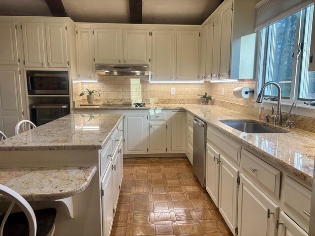 kitchen featuring appliances with stainless steel finishes, a sink, white cabinetry, and under cabinet range hood