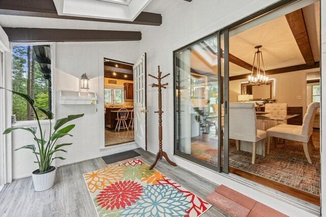 sunroom featuring lofted ceiling with beams and a notable chandelier